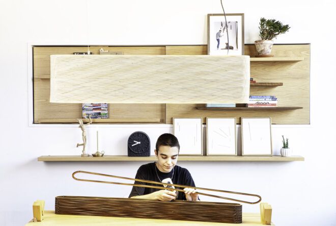A person in an office sits at a table constructing a lighting fixture.