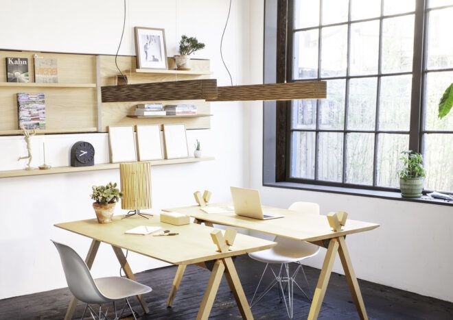 Lighting fixtures above two wood desks in an office space.