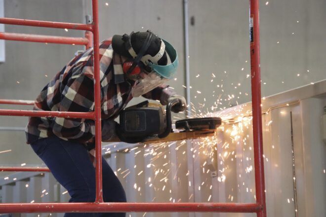 Sparks flying as a person with a saw works on a shipping container.