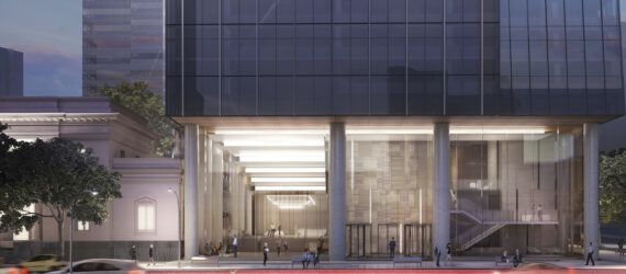 A long exposure shot of the street in front of an office tower lit up on the ground floor, with glass walls.
