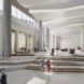 People walking through the lobby of an office building with white walls and floors and columns.