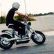 A sideview of a person wearing a helmet and driving an electric moped.