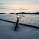 The front of an electric moped parked on a dock by the water.