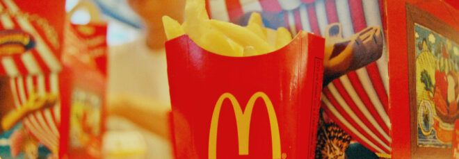 A cup of McDonald's fries in front of a Happy Meal box.