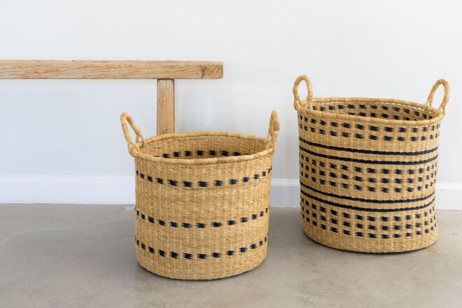 Two wicker-like baskets on the ground next to a wood bench.