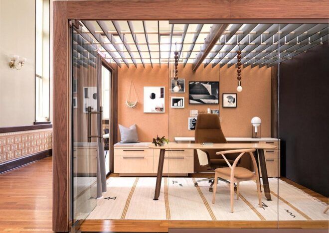 An office space with a wood frame and glass walls that look into a room with a desk and chair.