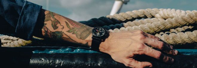 A tattooed arm with a watch on the wrist.