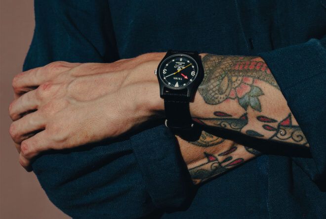 A tattooed arm with a watch on the wrist.