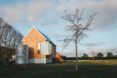 A green yard with a simple wood house with an attached steel water tank.