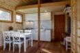 A wood kitchen/dining room with white counters, cabinets, chairs and dining table.