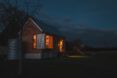 A simple wood house lit up at night.