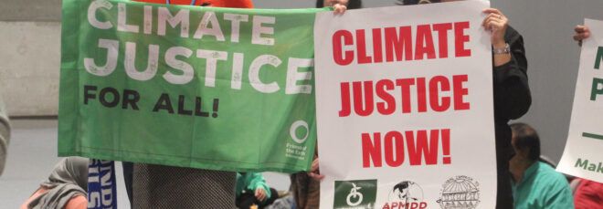 Two people holding climate justice signs at COP25.