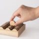 A hand picking up a wooden game piece.
