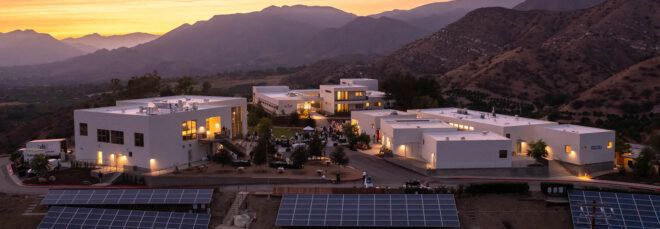 A landscape of solar panels in front of a campus.