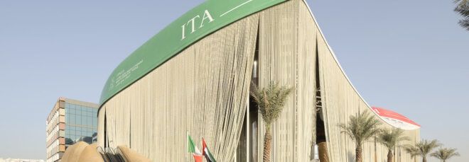 A massive pavilion with a green-color roof and a curtain-like facade.