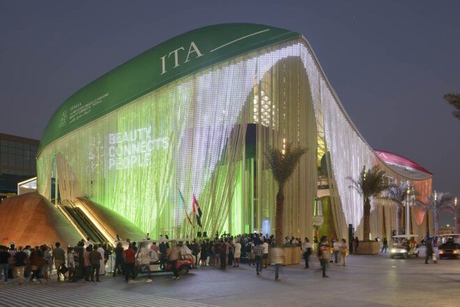 A massive pavilion lit up green at night.