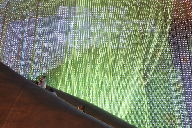 A string facade lit up green with white text reading "Beauty connects people."