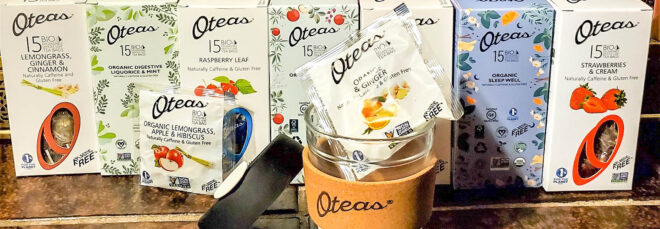 A line up of Oteas tea packages with a Oteas branded cup in front of them