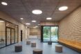 Wood-clad reception lobby with scattered seating poufs and a glass entry door