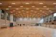 View of the court facing the entry lobby. Seating on the sides and a wood-clad ceiling with suspended lighting
