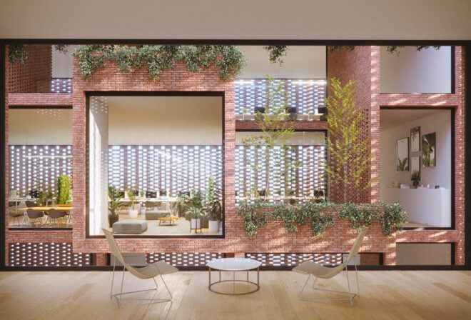 An indoor sitting area with two chairs and a coffee table next to a brick wall covered in plants.
