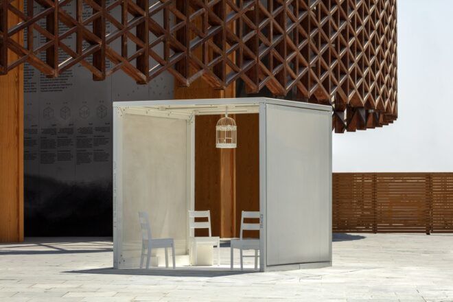 Four chairs on the ground and a bird cage hanging from the ceiling