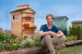 A person sitting in front of a Flow Pollinator House.