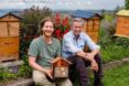 Two people sitting in front of a Flow Pollinator House.