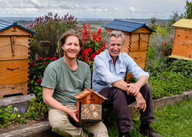 Two people sitting in front of a Flow Pollinator House.
