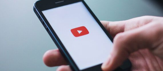 A hand holding a phone opened to YouTube.