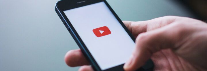 A hand holding a phone opened to YouTube.