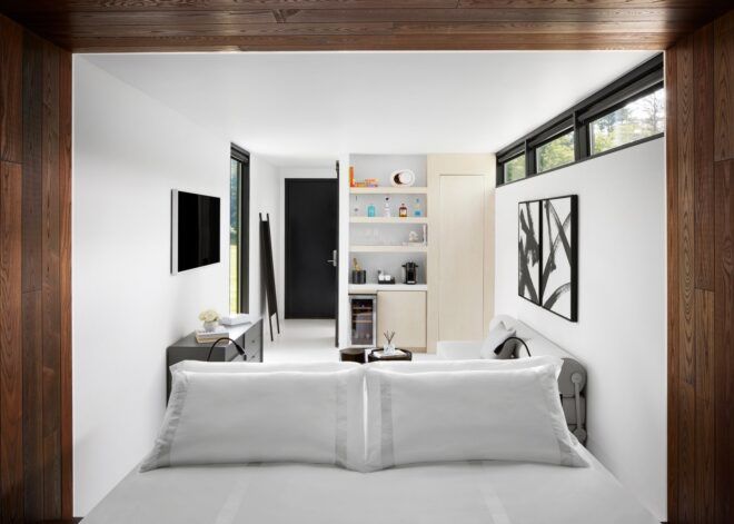 A room with a large bed in the foreground and shelves and a TV in the background