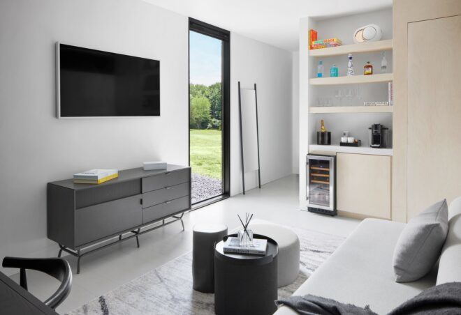 A white-walled living room with a TV set on a wall with a sofa facing it