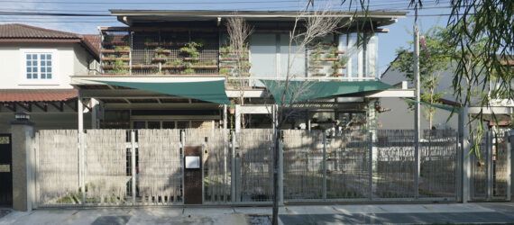A streetview of a two-level home with a green overhang covering part of the front yard.