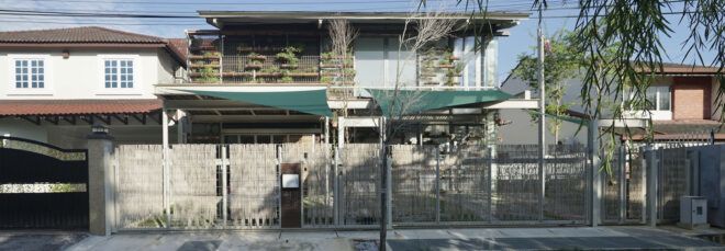 A streetview of a two-level home with a green overhang covering part of the front yard.