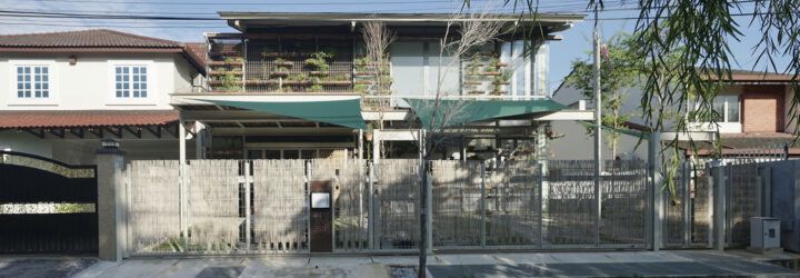 A streetview of a two-level home with a green overhang covering part of the front yard.