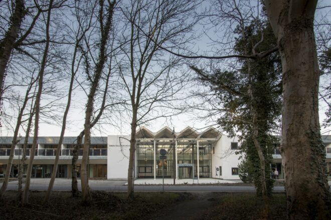 A white building with a forest in front of it