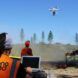 Workers flying drones in a burned forest area