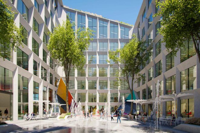 A courtyard with trees in front of a large white building with many windows.