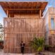 The exterior of a coconut palm wood home with a person standing out front.