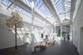 Hallway with trees, benches and a glass ceiling with a blue sky