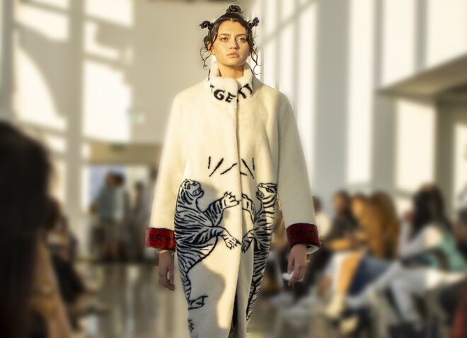 A model in a long-sleeved white coat with red trim and a tiger print.