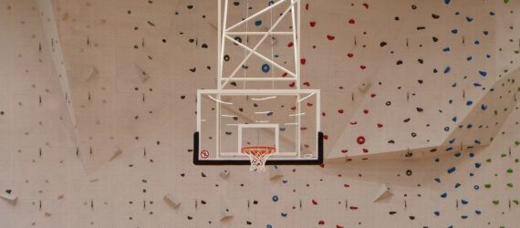A basketball hoop suspended in front of a rock climbing wall