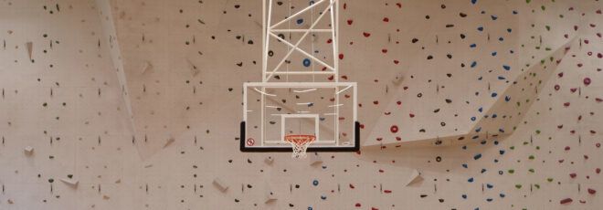 A basketball hoop suspended in front of a rock climbing wall