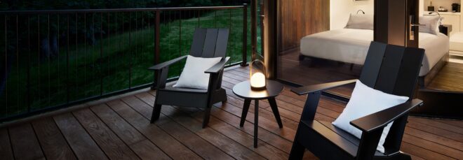 Two black chairs with white pillow cushion on it sitting out on a deck at night