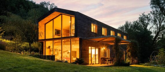 A wooden house with lights on inside full of windows