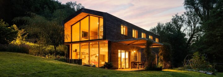 A wooden house with lights on inside full of windows