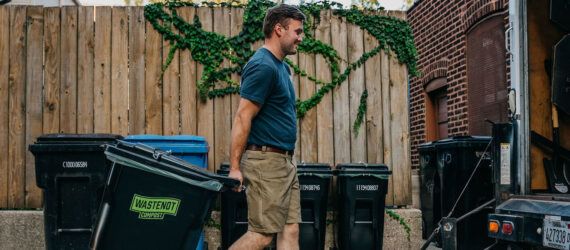 A person moving a trash bin.