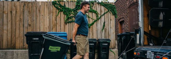 A person moving a trash bin.