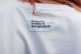 A person wearing a white t-shirt with a label reading 